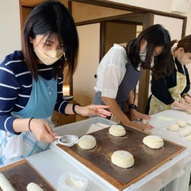 パン作りの仕上げ作業・茶漉しで飾りの粉をふるう生徒さんの様子