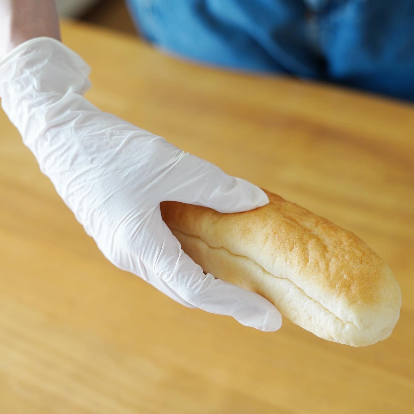ニトリル手袋Sサイズ白（粉なし）を手にはめてパンを持っています